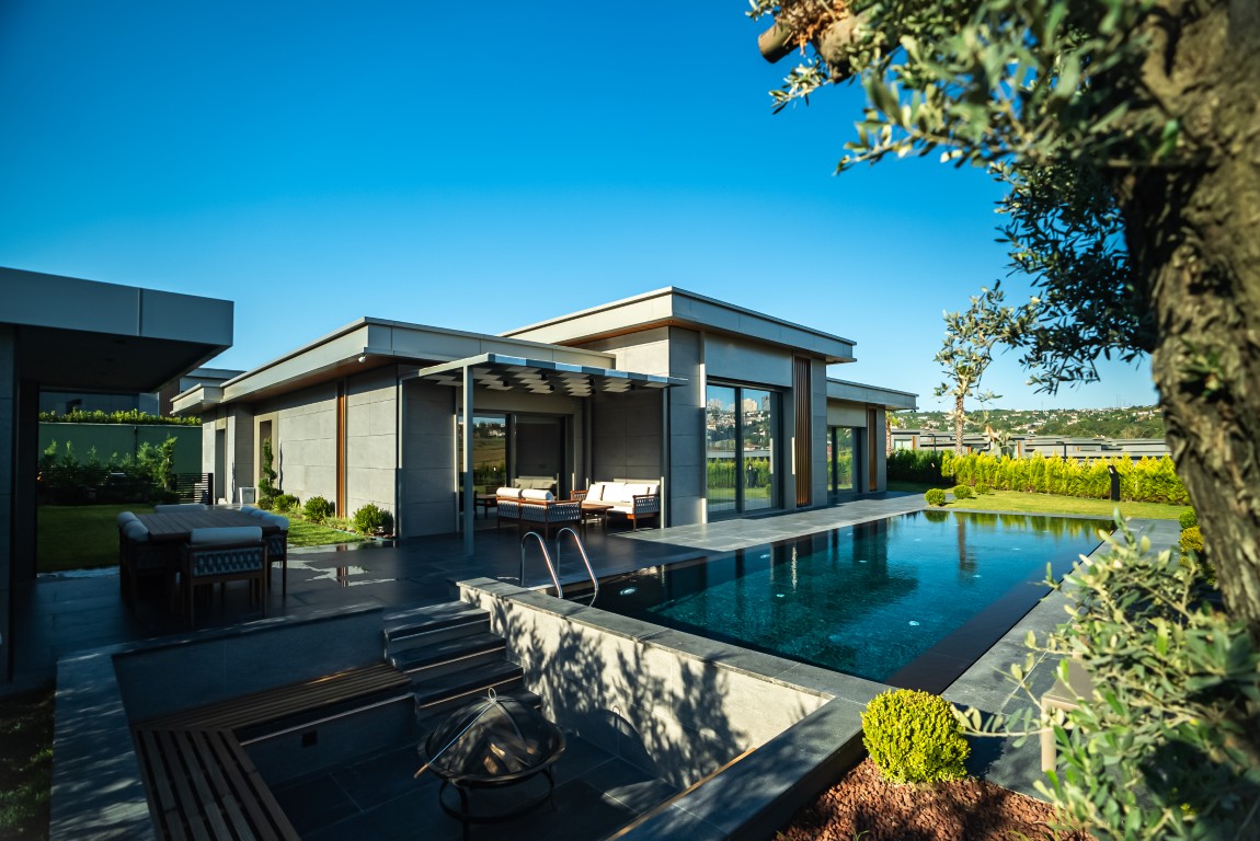 jpg displaying modern stone cladding architecture, a private swimming pool with a sunbathing terrace, and a cozy sunken fire pit area.
