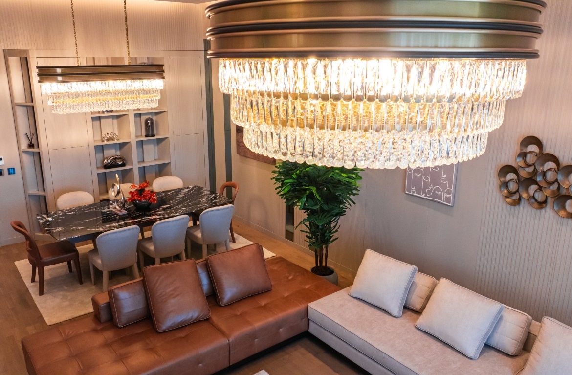 jpg showing a sophisticated living and dining area with luxury furniture, modern chandeliers, and large windows.