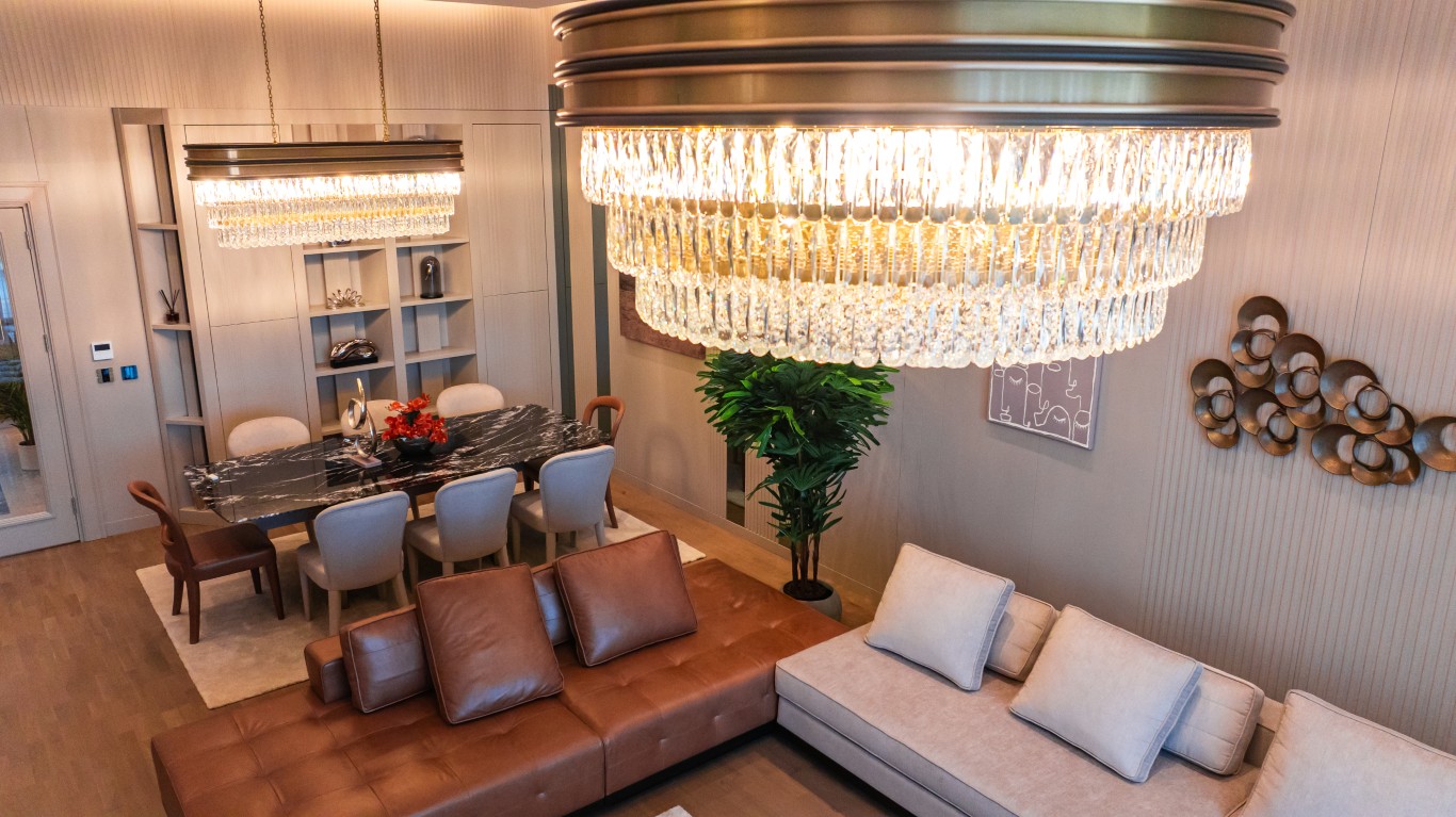 jpg showing a sophisticated living and dining area with luxury furniture, modern chandeliers, and large windows.