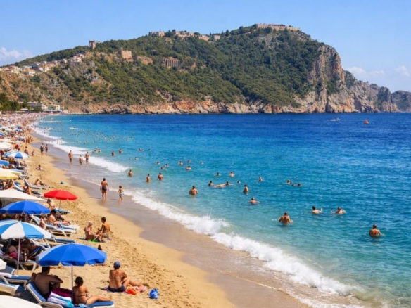 Weitblick auf den Kleopatra-Strand und die Burg von Alanya an einem sonnigen Tag.