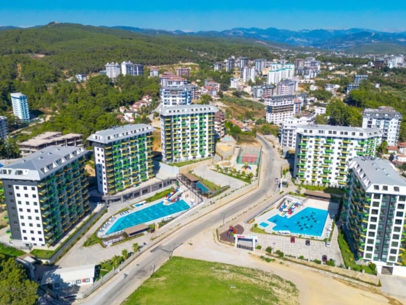 Вид с дрона на элитный жилой комплекс «Konak Green Towers» в Авсалларе (Алания), в котором имеются большие бассейны и аквапарк, а сам комплекс окружен сосновыми лесами.
