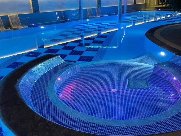 Upplyst utomhuspool nattetid i bostadskomplexet Konak Twin Tower 2 i Cleopatra, Alanya