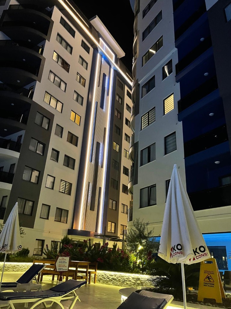 Exterior night view of the illuminated multi-story residential building facade of Konak Twin Tower 2 in Cleopatra Alanya