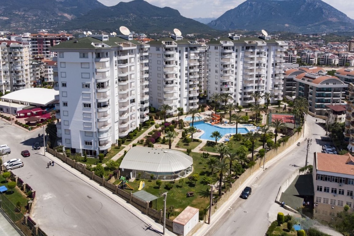 High-angle view of the Galaxy complex featuring an outdoor pool and tennis court, offering a 2 bedroom apartment for sale in Cikcilli Alanya