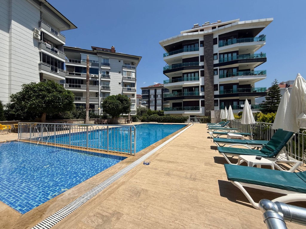 Outdoor swimming pool and sun loungers at Royal Sitesi featuring a 2 bedroom beachfront apartment for sale in Kestel Alanya