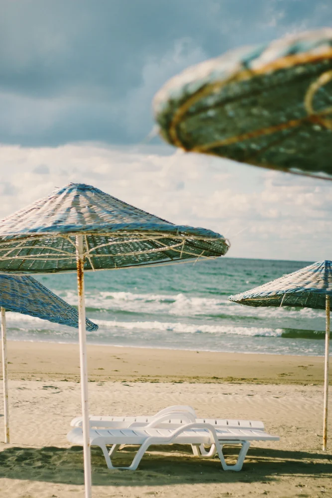 Sun loungers and beach umbrellas · illustrative coastal photograph